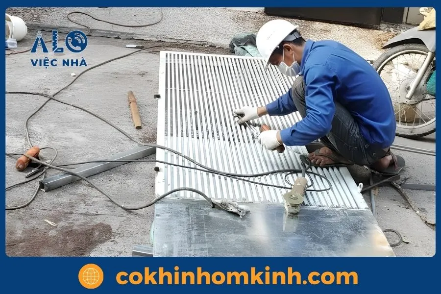 Dịch vụ Sửa Cửa Sắt tại tphcm GIÁ TỐT năm 2026 7 Kỹ thuật viên cơ khí dùng dụng cụ chuyên dụng điều chỉnh bản lề cửa sắt bị lệch.